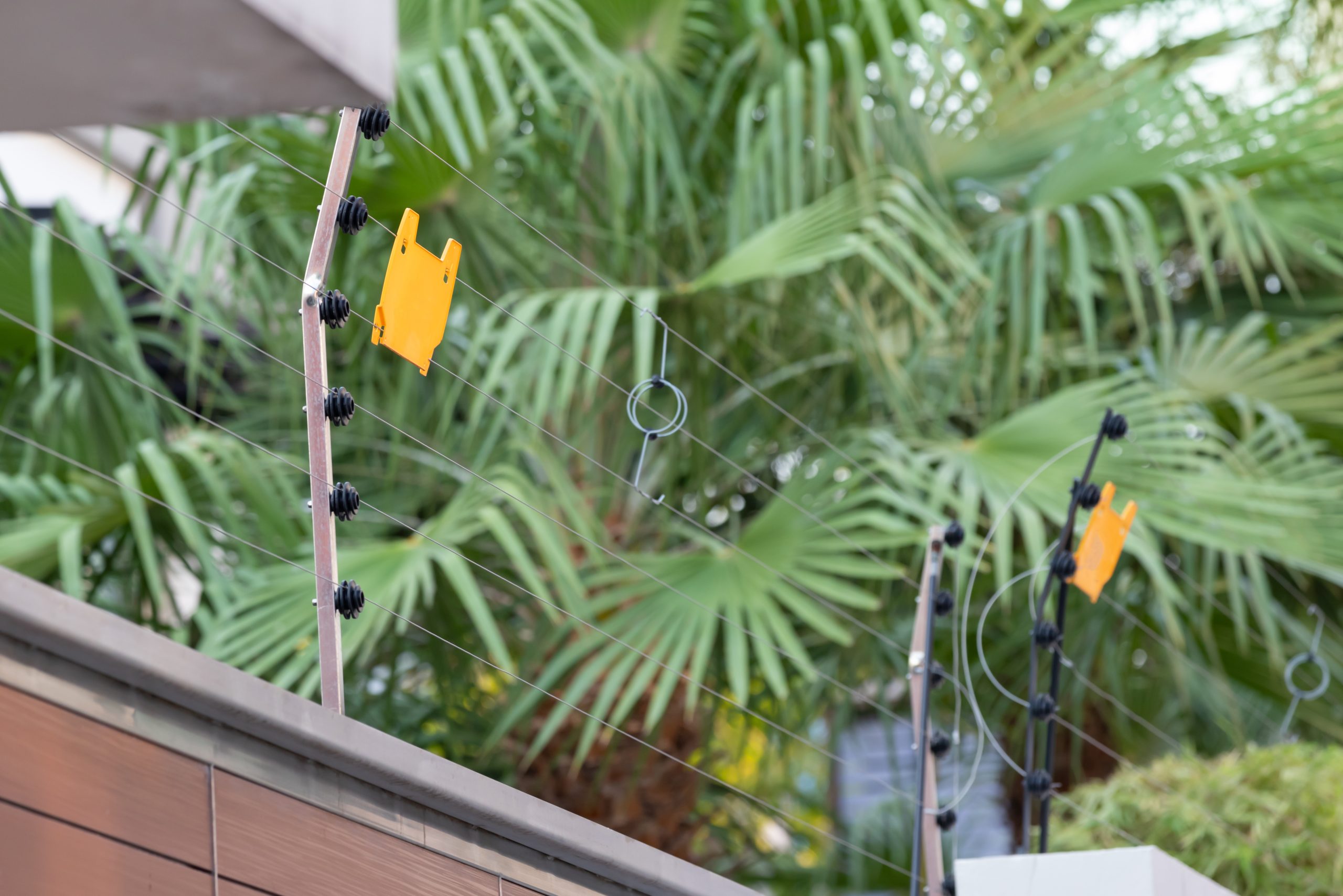 high voltage security fence on house wall with blank yellow plastice sign.